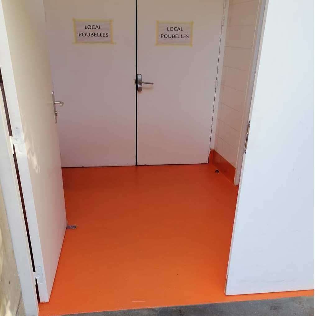 Sol de toilettes publiques avec revêtement en résine orange vif, offrant esthétique et facilité de nettoyage.